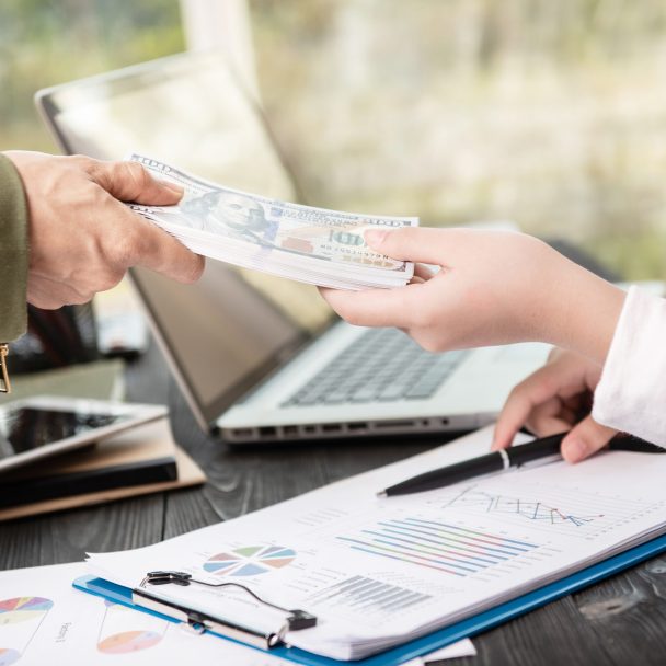 businessman giving money to his partner while making contract - bribery and corruption concepts.